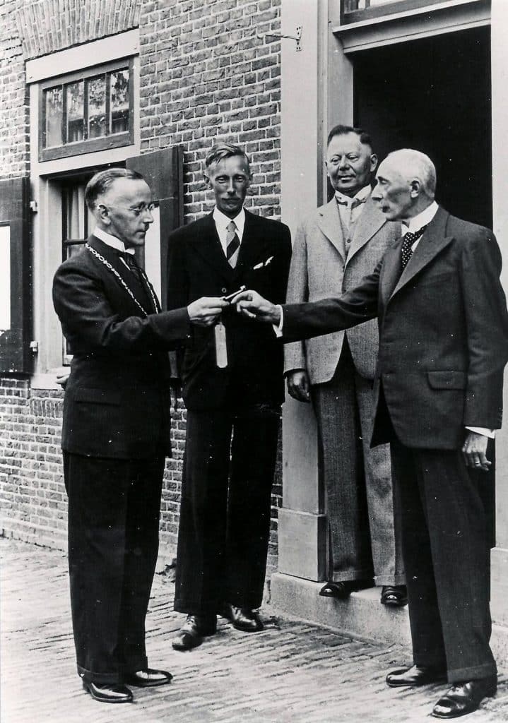 De burgemeester overhandigd de sleutel aan het hoofd van de openbare school.