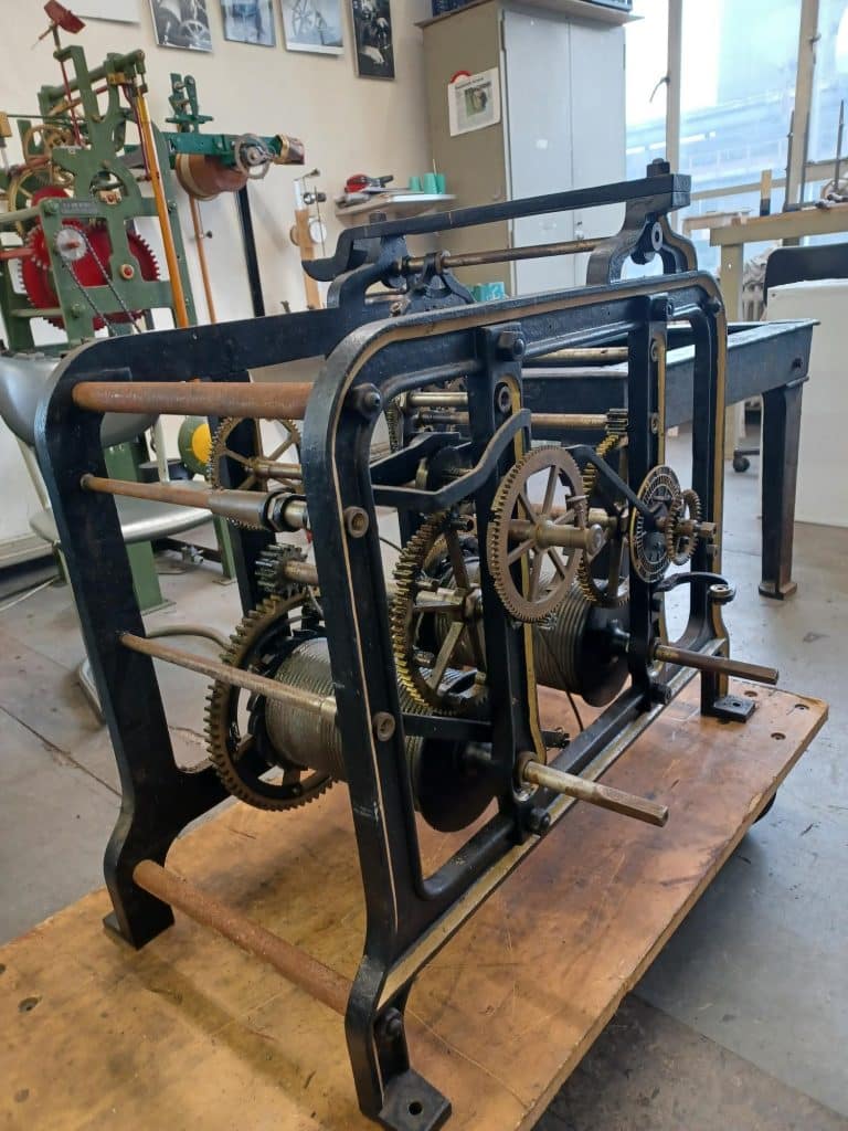 Proefopstelling in de werkplaats, uurwerk uitgevoerd met slingervanger en opwindunit (beneden onder het uurwerk).