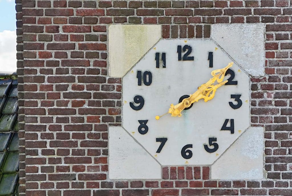 De klassiek versierde en vergulde wijzers staan in contrast met de Art Deco vormgegeven wijzerplaat. Deze is van kalkstenen met verhoogde zwarte moderne cijfers. Dit is de kerkklok van de voormalige Dorpskerk in Oterleek.