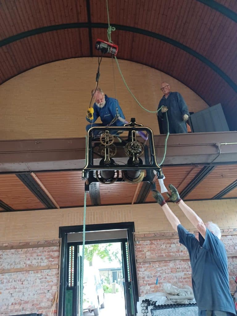 Vrijwilligers van de stichting hijsen het uurwerk vanaf het plateau in de Dorpskerk Oterleek.
