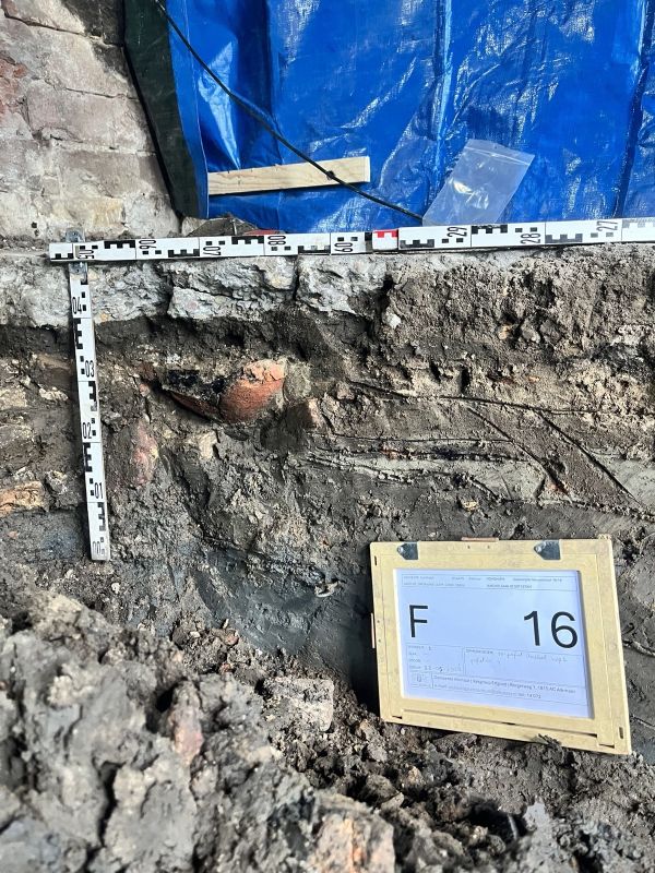 Een terra cotta kleurige schaal is ingegraven in een muur in de hoek van een pand