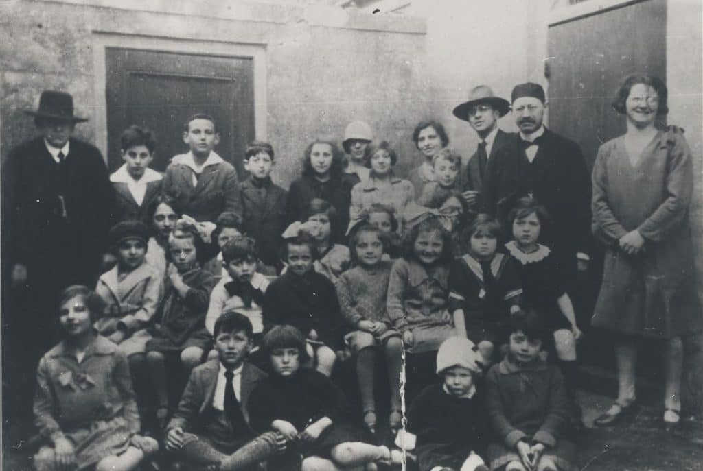 Groepsfoto van zeven volwassenen en een groep kinderen.
