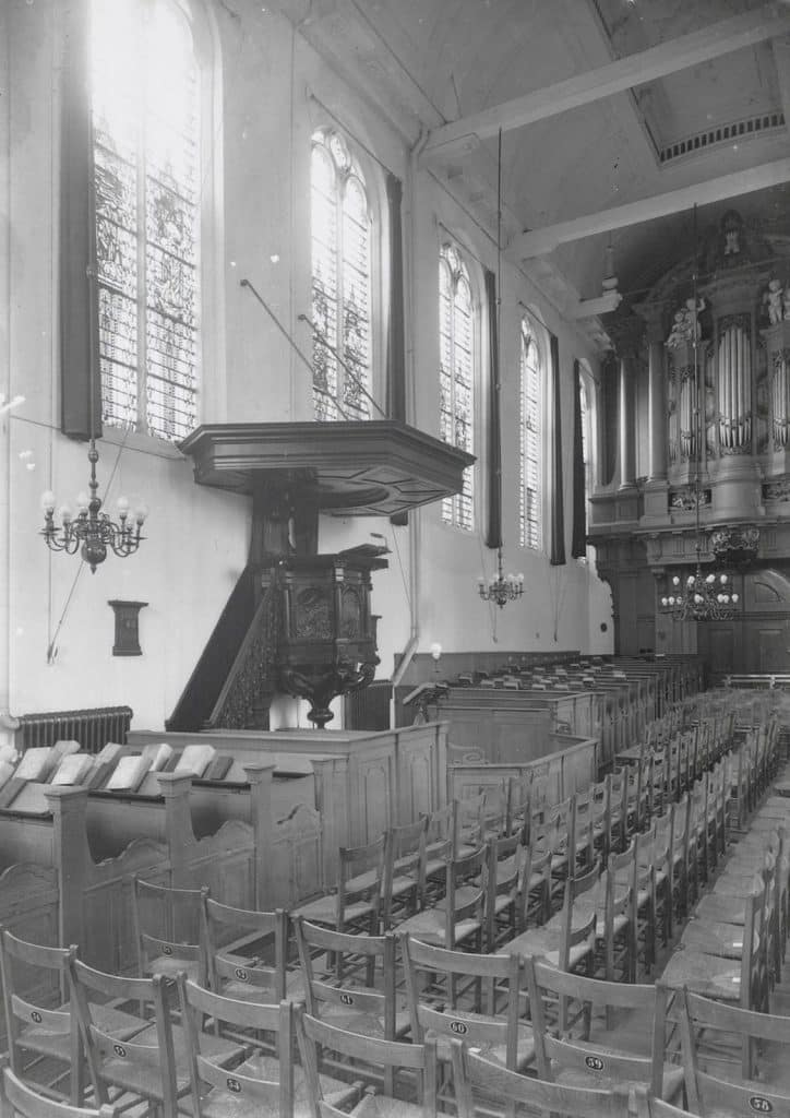Het interieur van de Kapelkerk in circa 1935, zal er vrolijk uitgezien hebben. De kleurige doorstraling van de glas-in-loodramen aan deze zuidkant. De kleuren zijn helaas onbekend.