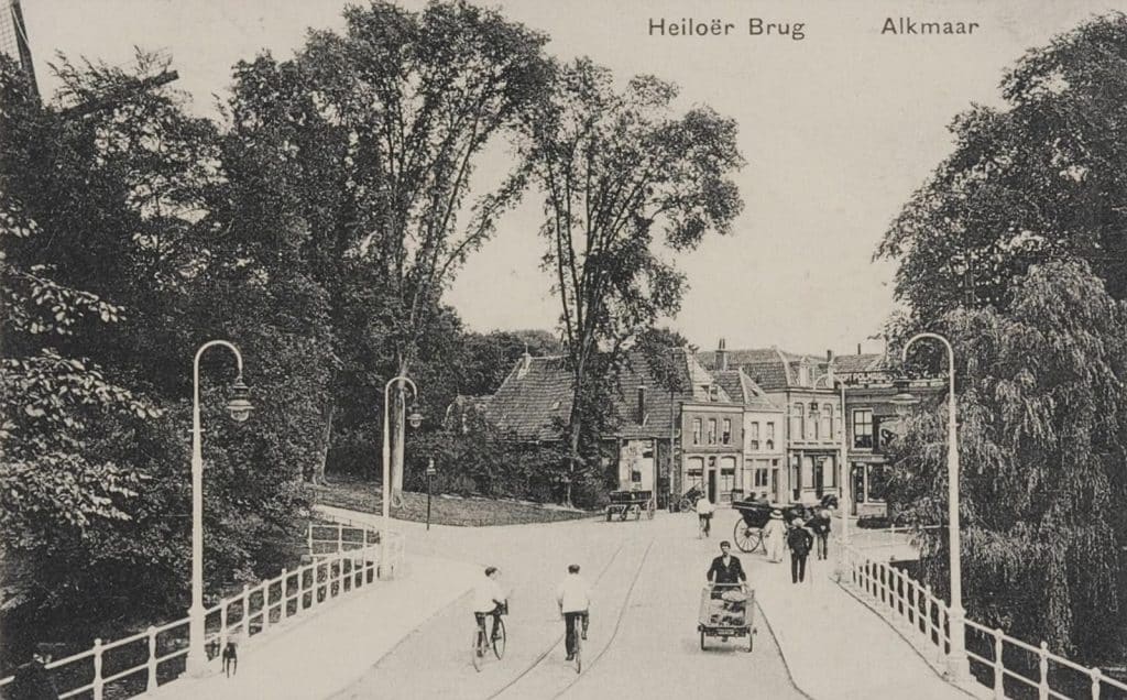 Op straat zijn onder meer een rijtuig, een handkar en een paar fietsers te zien. In het midden van de weg ligt de rails van de stoomtram.
